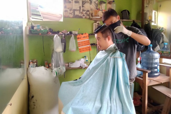 Danang (27) melayani pelanggan di salon potong rambut miliknya, di kawasan Pasar Pon Blora Kota, Kabupaten Blora