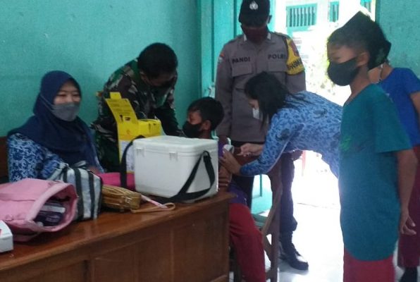 Kegiatan vaksinasi Covid-19 untuk anak-anak digelar di Sekolah Dasar IT NU Walisongo Desa Wado Kecamatan Kedungtuban, Senin (17/01). Beberapa anak yang takut di suntik mencoba ditenangkan oleh anggota TNI dan Polri.