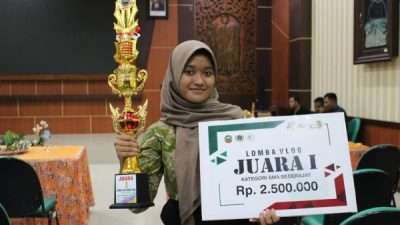 Novegnita Velysya Putri Adelia berpose sambil memegang tropi.